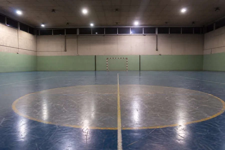 Empty indoor futsal court with a worn centre circle