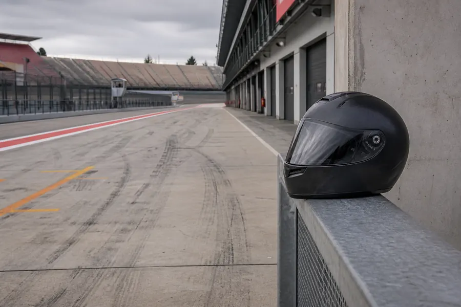 Racing helmet on a metal barrier in a concrete paddock